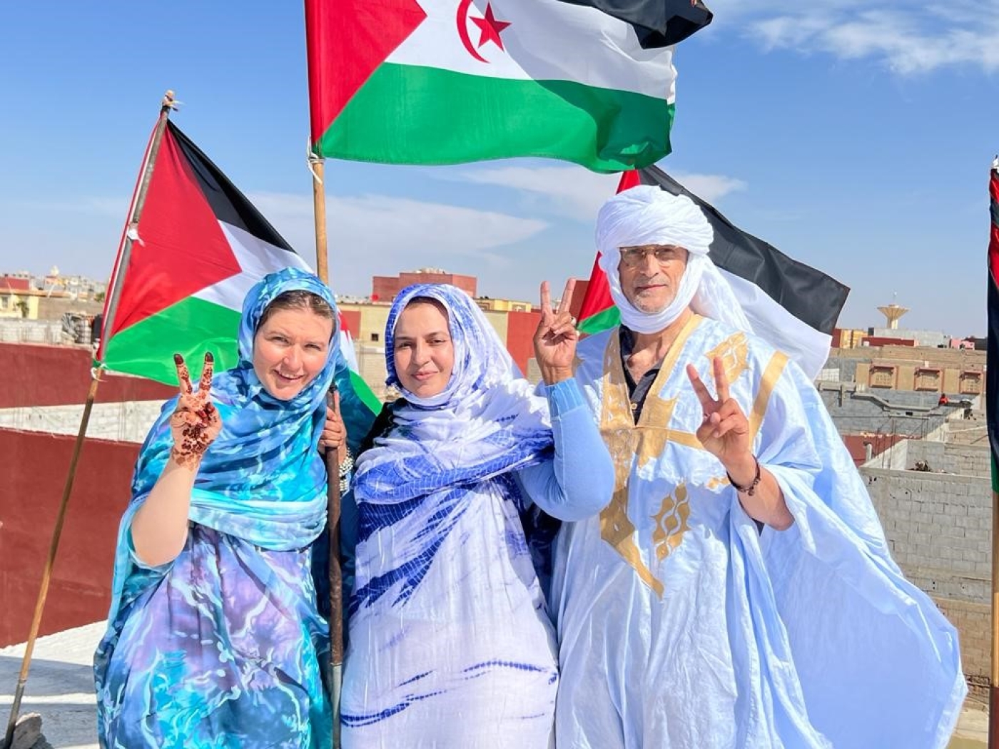 Ruth McDonough, Sultana Khaya et Tim Pluta sur le toit de la maison de Sultana Khaya à Boujdour, agitant le drapeau sahraoui (photo fournie)