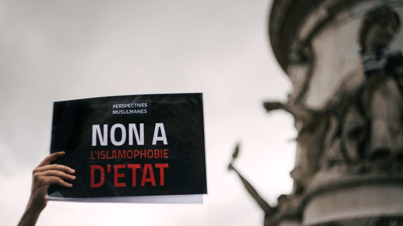 A French protester carries a banner that reads 'no to the islamophobia of state' during a rally against Islamophobia in Paris on 3 September, 2022 (Reuters) 