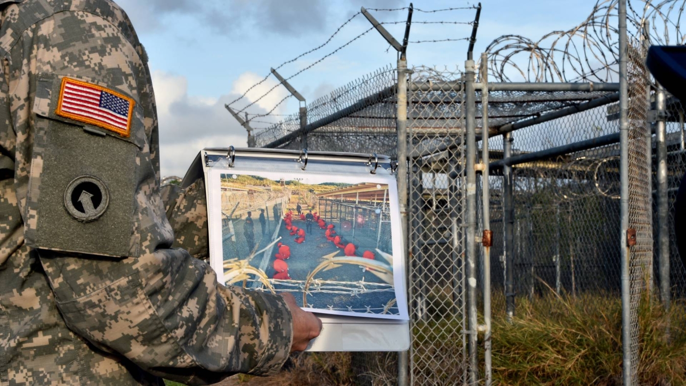 A US Army officer shows a photograph of the now-abandoned "Camp X-Ray" detention facility at the US Naval Station in Guantanamo Bay, Cuba on 9 April 2014