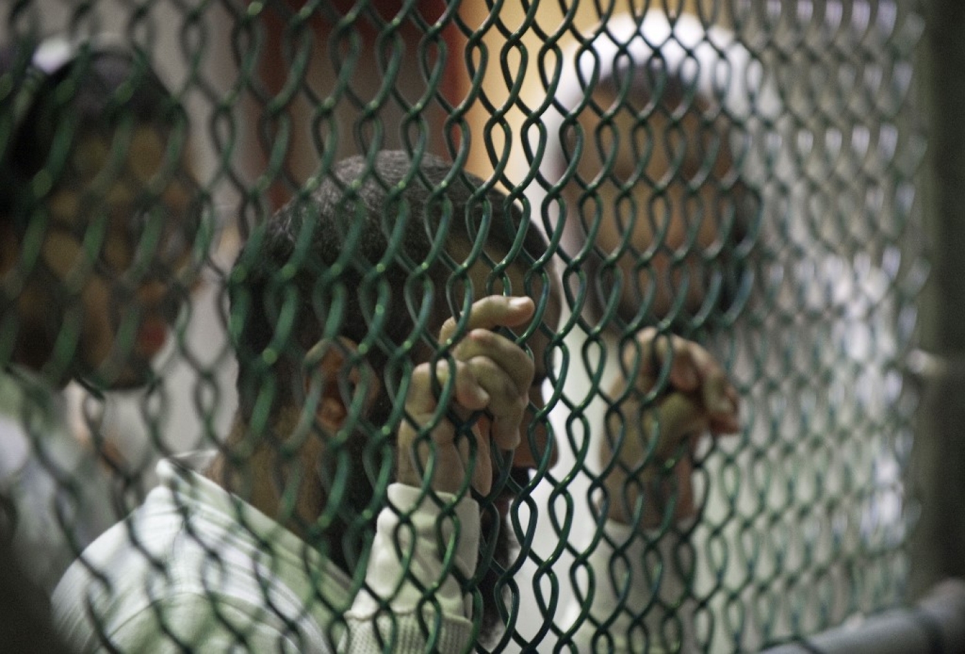 Detainees line up at a chain link fence for library books and magazines inside Camp VI at Guantanamo Bay prison in 2010