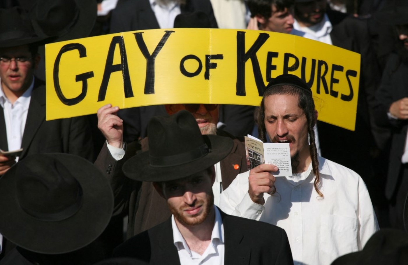 Un homme juif ultra-orthodoxe prie tandis qu’une pancarte anti-gay est brandie derrière lui, lors du défilé de la Gay Pride d’Israël à Jérusalem, le 21 juin 2017 (AFP/Menahem Kahana)