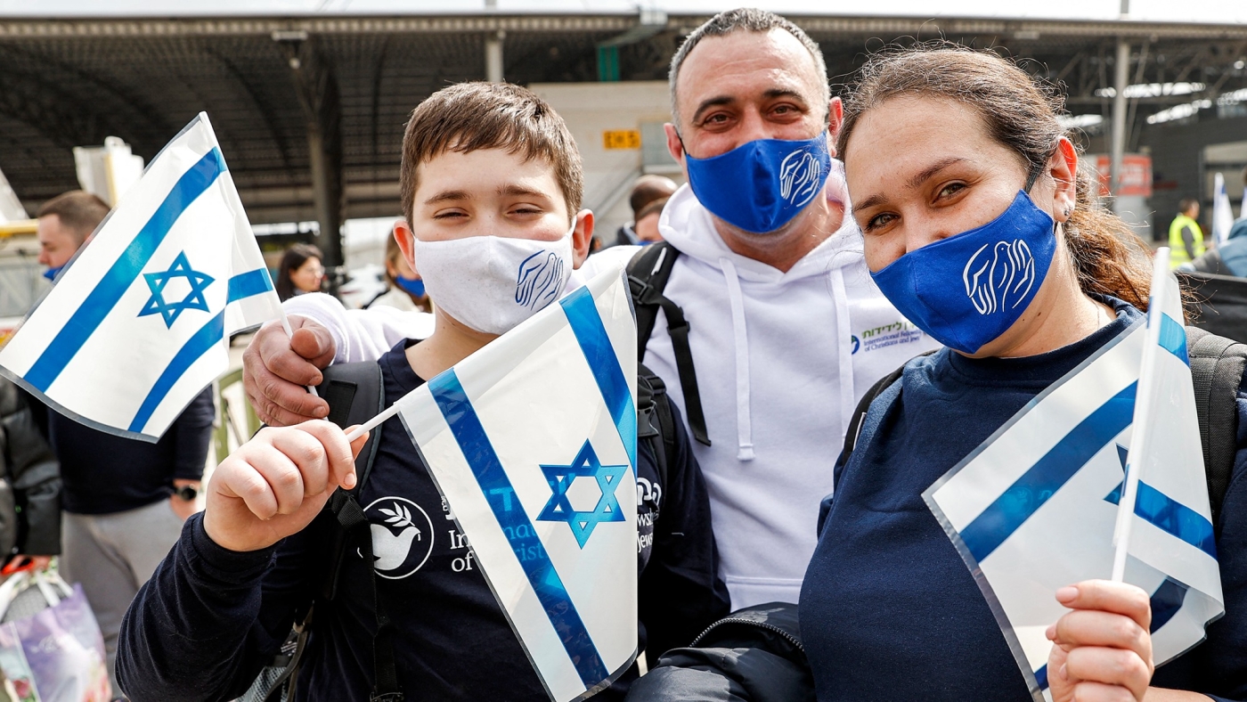 Immigrants from Ukraine wave Israeli flags after arriving at Israel's Ben Gurion Airport in Lod on 20 February, 2022 (AFP)