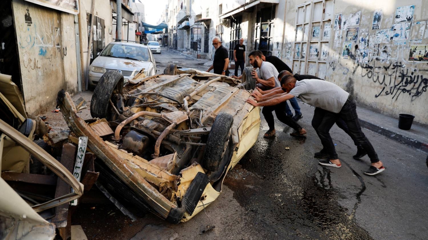 Palestinians try to move a damaged car after the Israeli army's withdrawal from the Jenin camp, in Jenin, in the Israeli-occupied West Bank 5 July 2023.