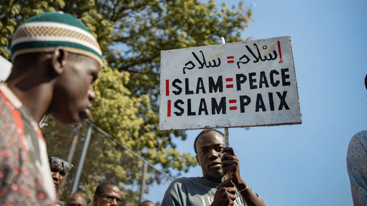 A man holds up a sign "Islam = peace" during a protest in Bamako, Mali on 4 November 2022 (AFP)