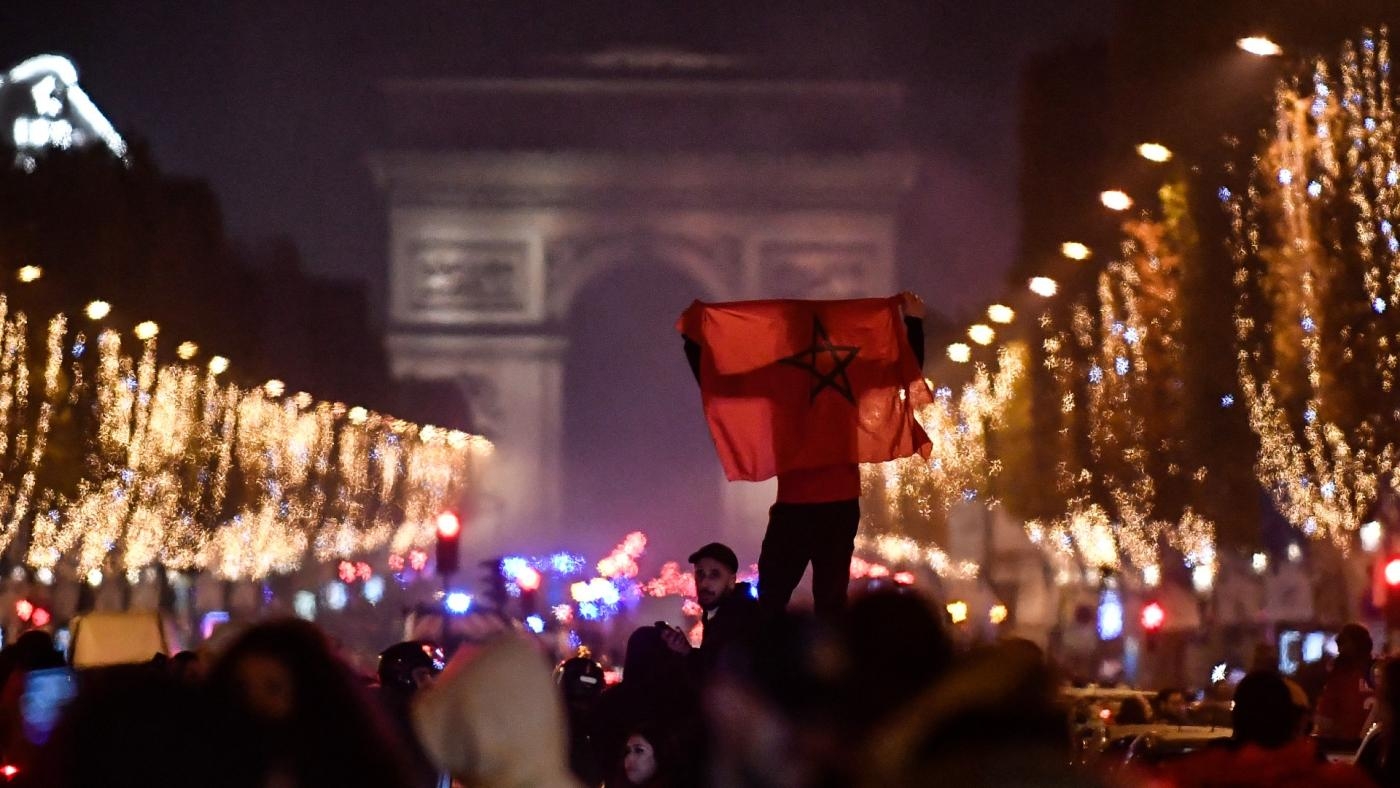 Un supporter marocain brandit un drapeau près de l’Arc de triomphe à Paris pour fêter la victoire des Lions de l’Atlas sur l’Espagne au Mondial, le 6 décembre 2022 (AFP)