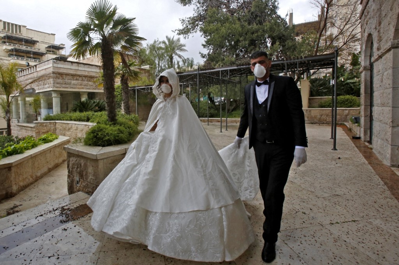 Newly-wed Palestinians head to have their pre-wedding photo shoot in the garden of a hotel in the city of Bethlehem in the occupied West Bank on 10 April 2020 (AFP)