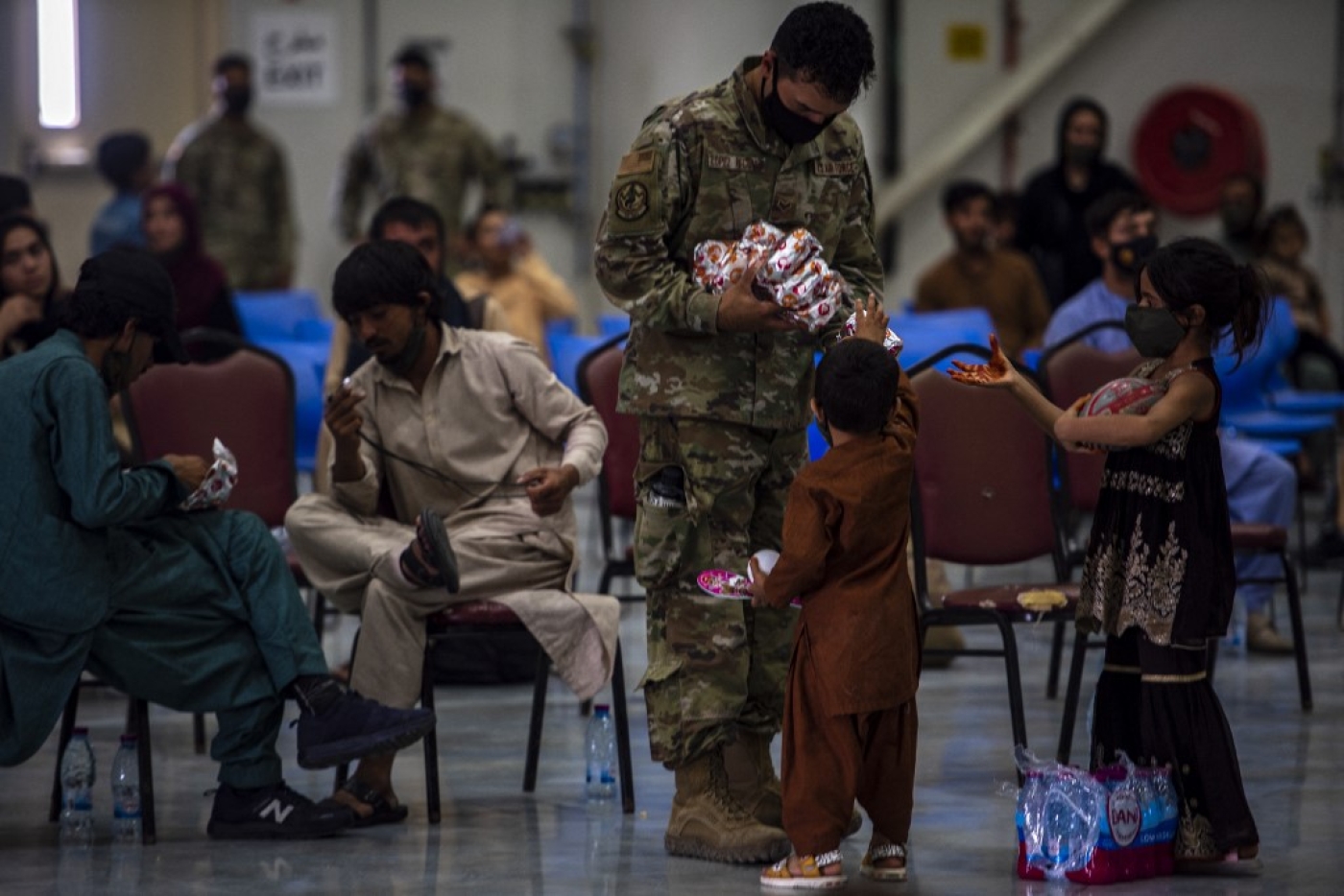 A US soldier distributes food to Afghan citizens on 16 August 2021, at Al Udeid Air Base, Qatar.