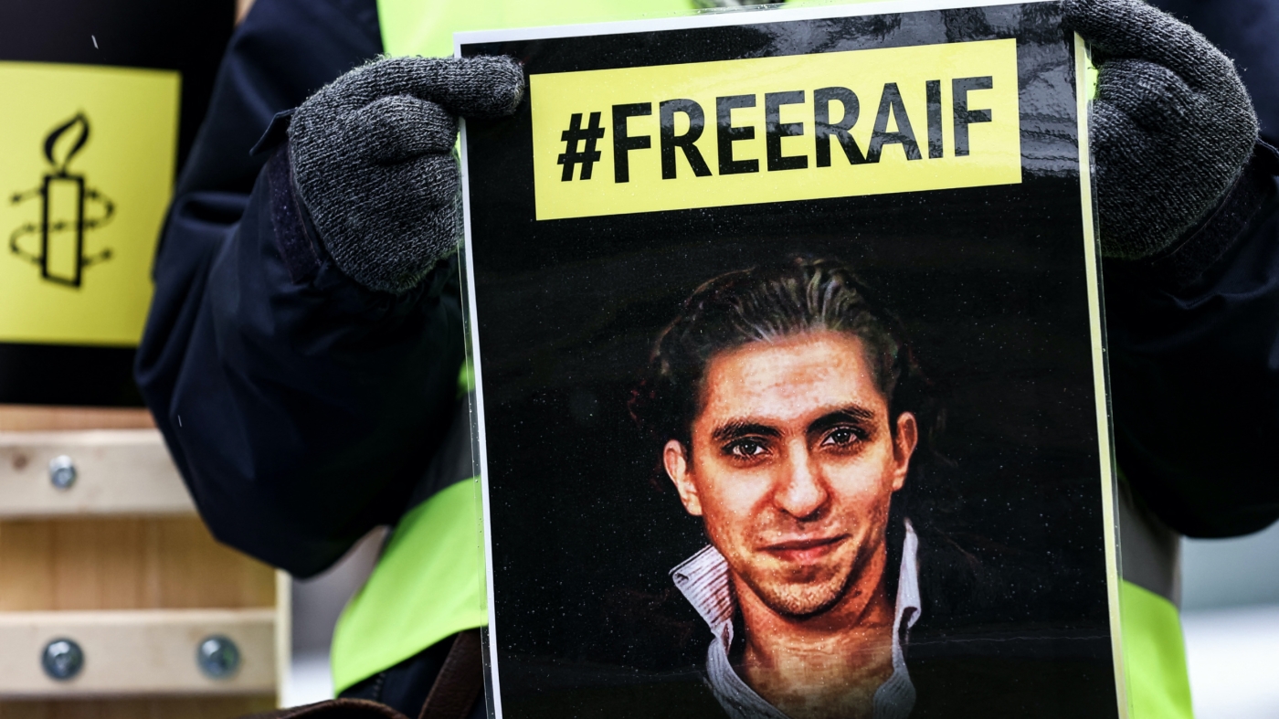 An activist of the human rights NGO Amnesty International holds a portrait of Raif Badawi in front of the embassy of Saudi Arabia in Brussels, 8 January 2021 