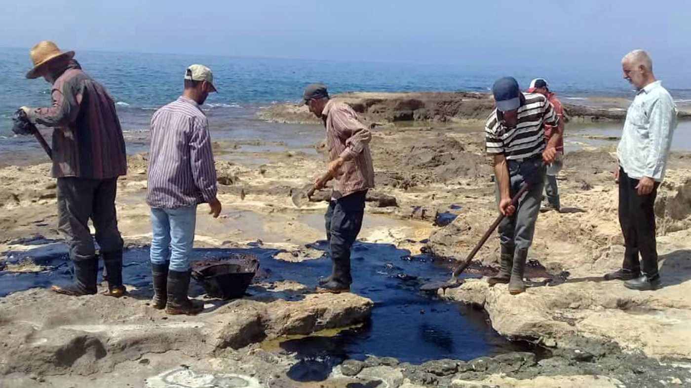 People clean Syria's Mediterranean coast on 31 August 2021 following an oil leak from the Baniyas power plant.