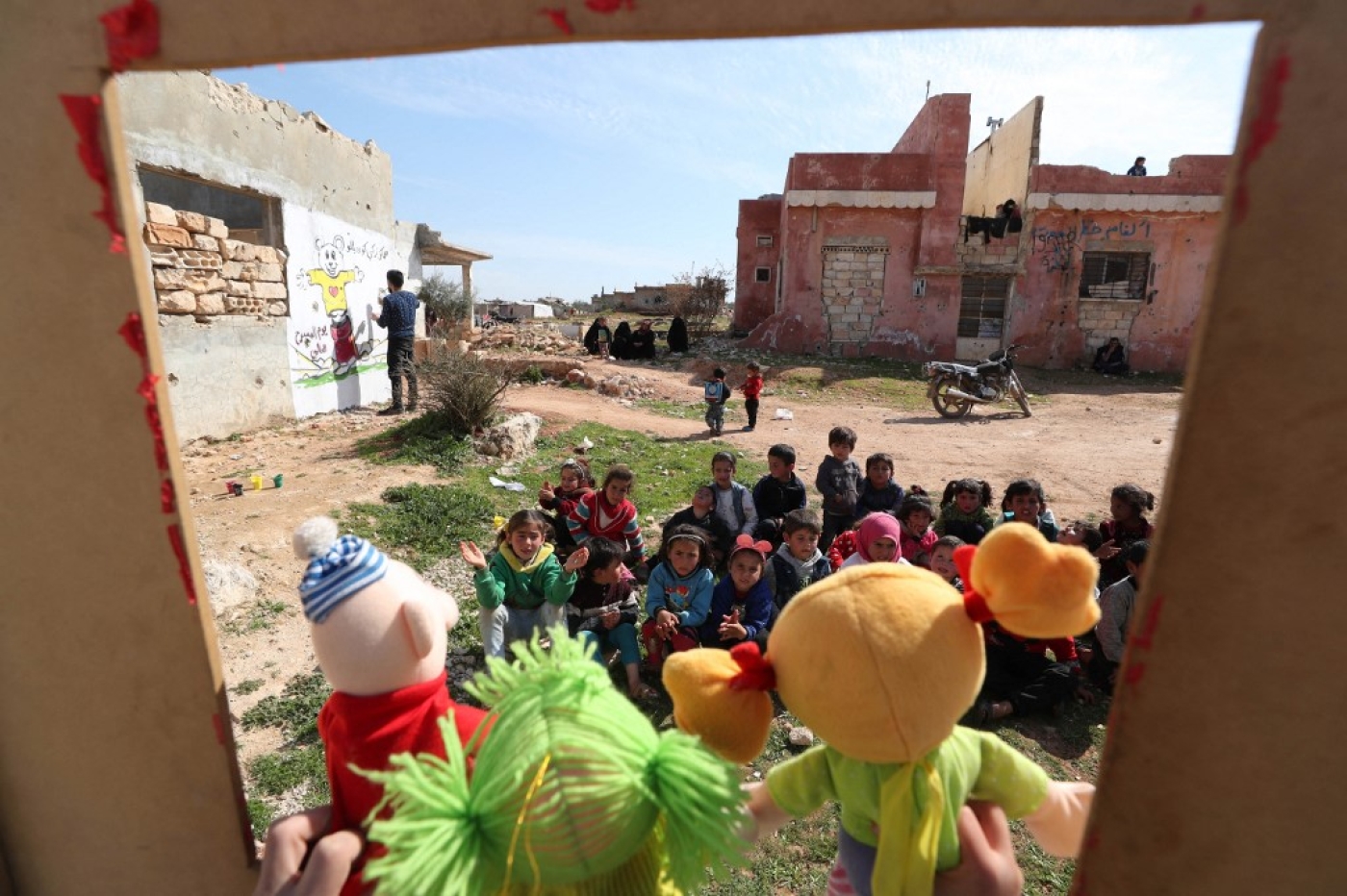 Syrian children watch a puppet show amid the ruins of buildings destroyed during Syria's civil war in the northwestern Idlib province on 30 March 2021.