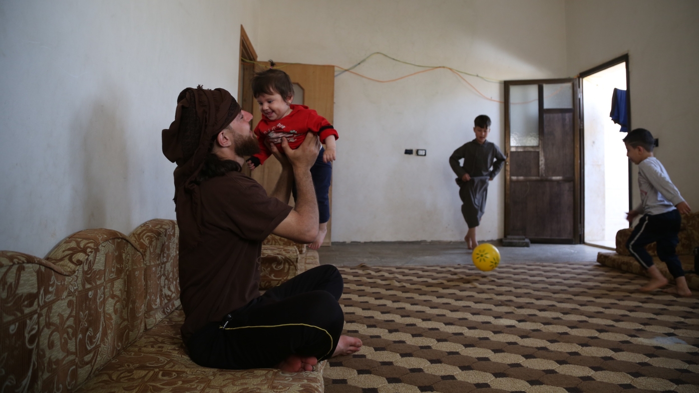 Syrian refugee Ahmed Moaz plays with his children during a visit home during the Eid holiday (MEE/Bilal al-Hammoud)