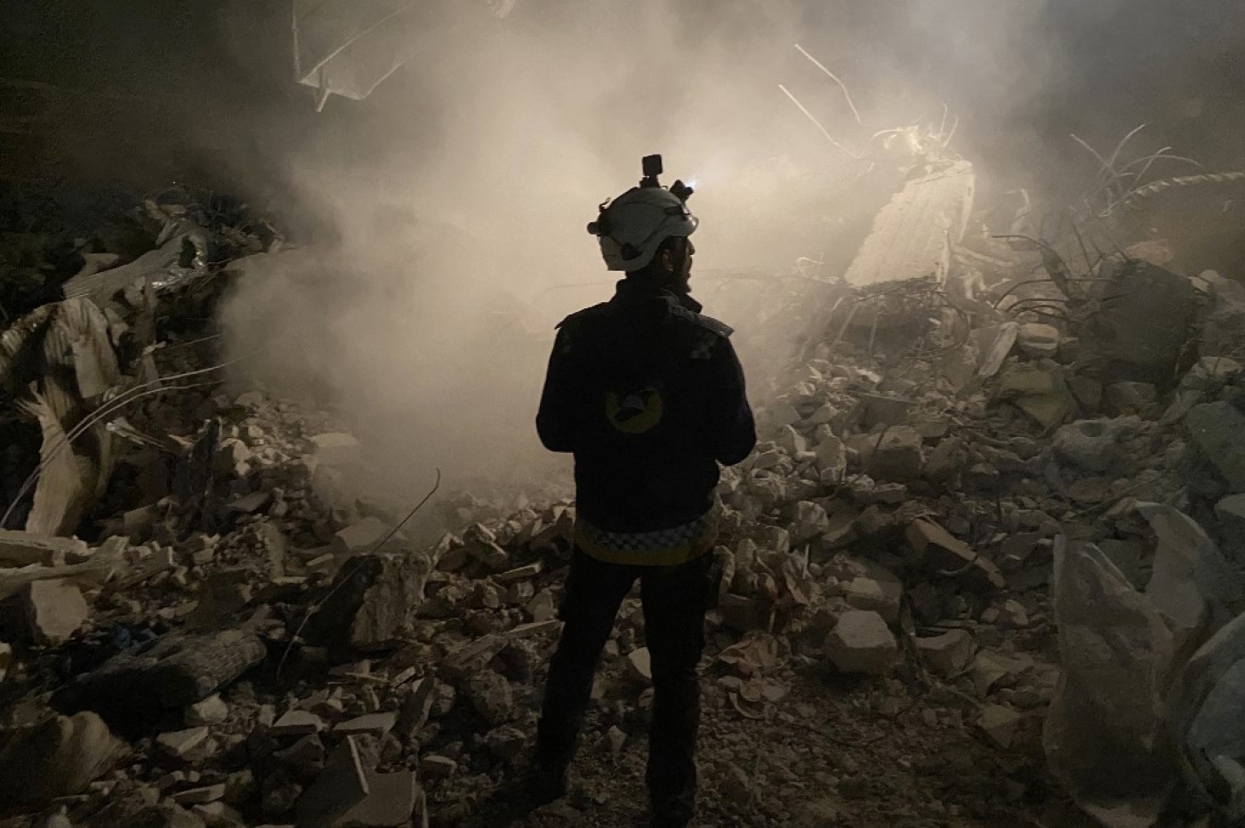 Un membre des Casques blancs se tient devant les décombres d’un immeuble lors de la recherche de survivants dans la ville syrienne tenue par les forces antigouvernementales de Jaindairis, le 8 février 2023 (AFP)