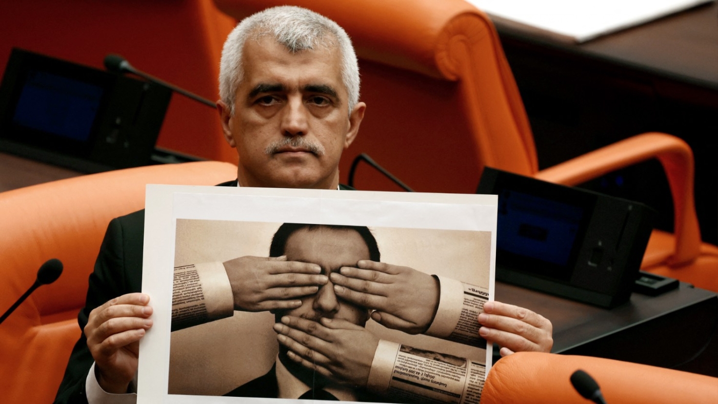 Omer Faruk Gergerlioglu, an MP for the pro-Kurdish HDP, holds a photograph depicting censorship during a session on a bill that criminalises "disinformation" on 13 October 2022 in Ankara.