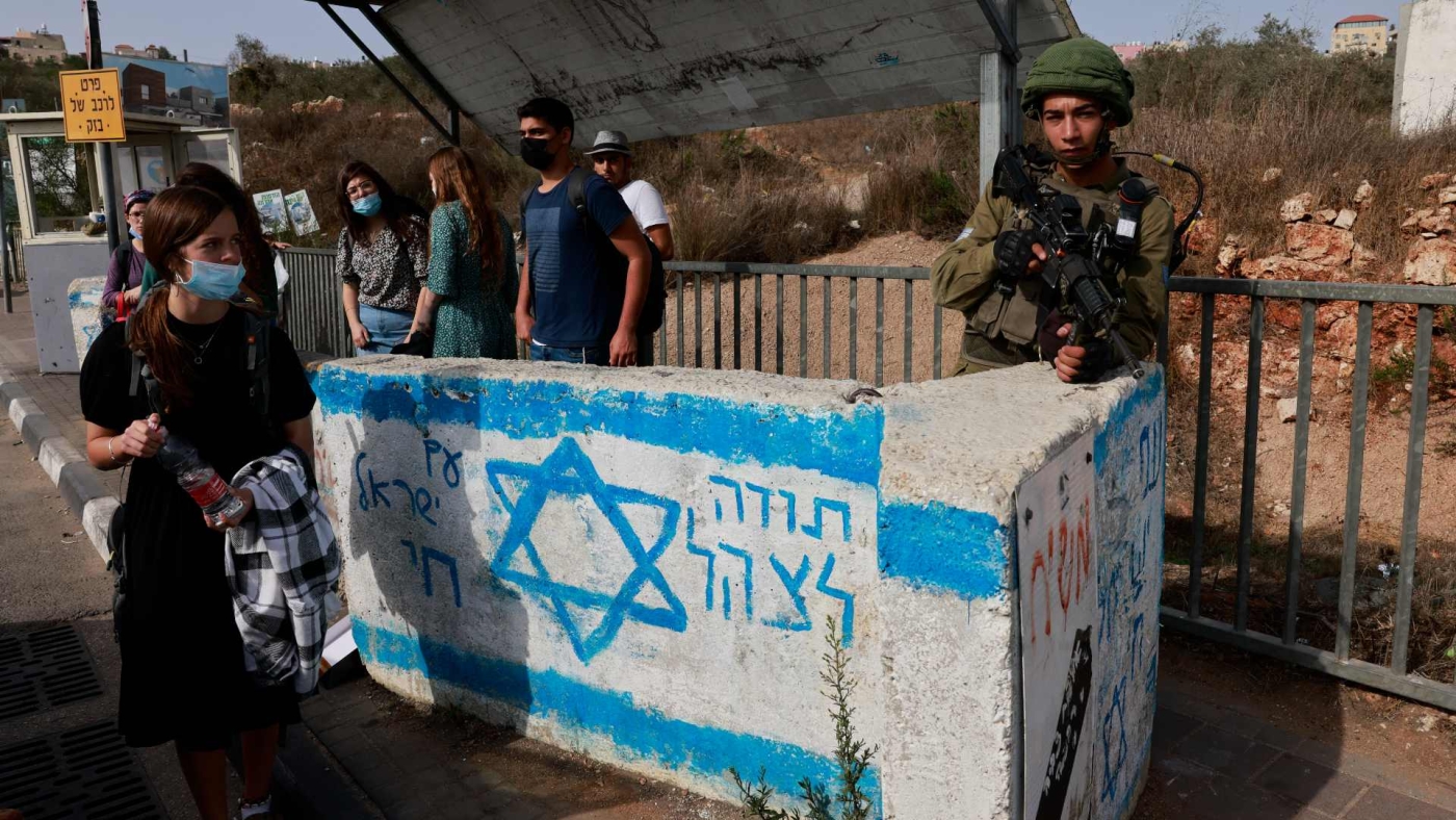 An Israeli soldier stands on guard at a bus station near the Israeli settlement of Ariel in the occupied West Bank on 14 October 2021.