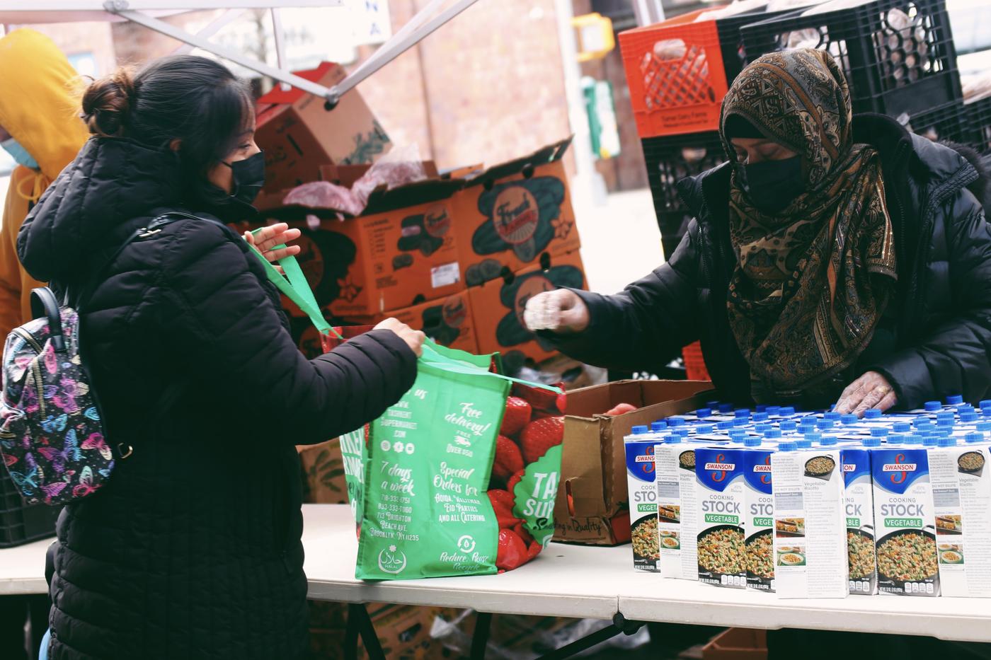 A volunteer handing out food items to a person who accesses the pantry in Brooklyn.