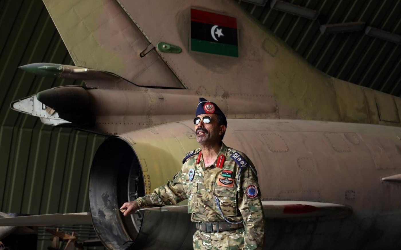 Un porte-parole de l’armée du GNA se tient à côté d’un MiG-23 partiellement en pièces sur la base aérienne d’al-Watiya, le 18 mai 2020 (AFP)
