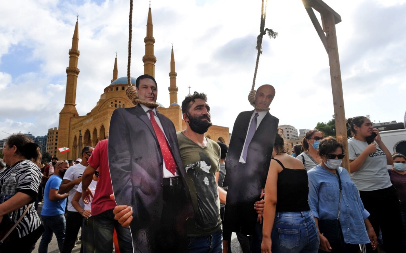 Un homme pose avec une découpe en carton du Premier ministre Hassan Diab et du président exécutif des Forces libanaises Samir Geagea pendus à Beyrouth le 8 août 2020 (AFP)