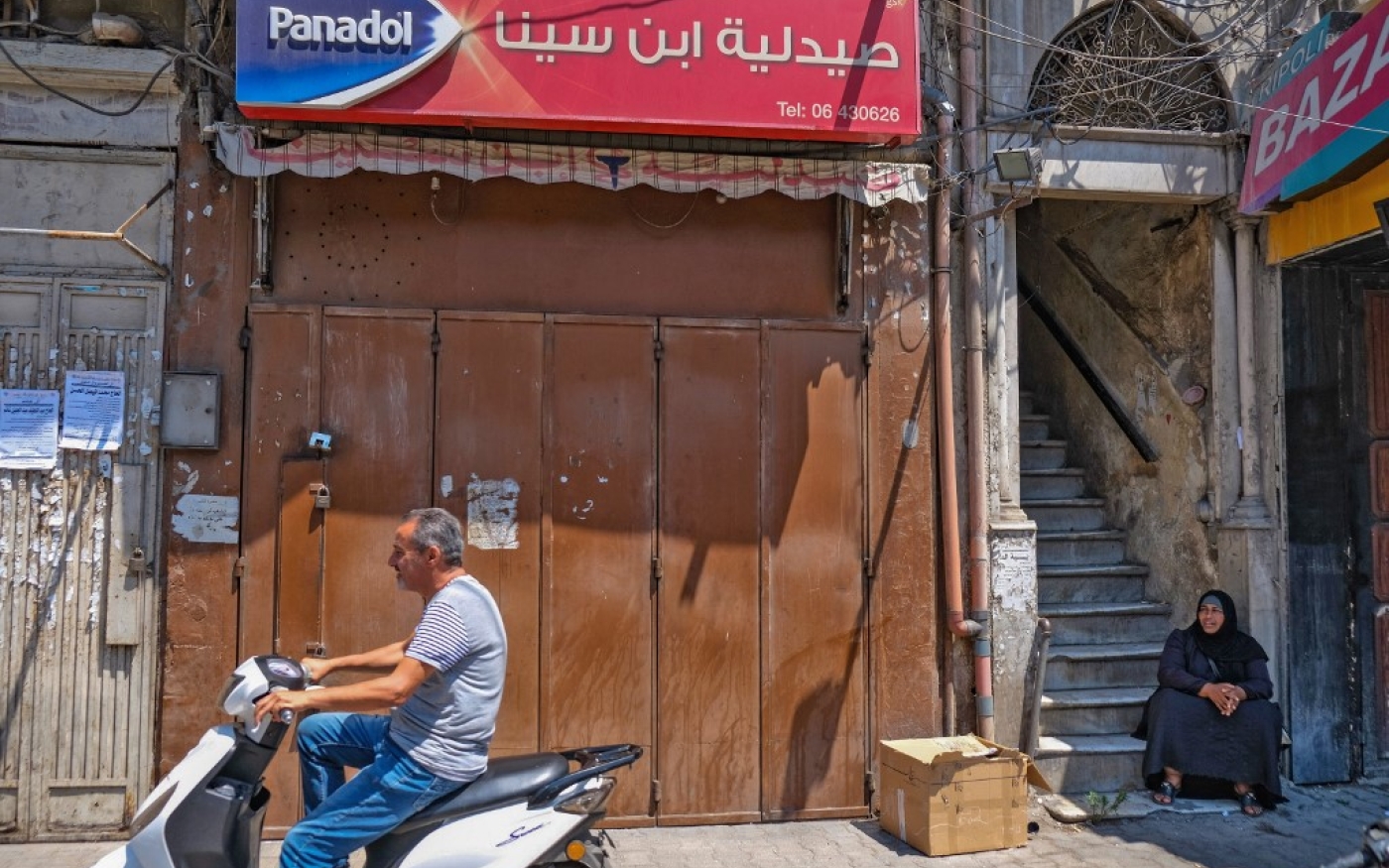 Un homme passe à scooter devant une pharmacie fermée de Tripoli lors d’une grève nationale pour protester contre une grave pénurie de médicaments, le 9 juillet 2021 (AFP/Ibrahim Chalhou)