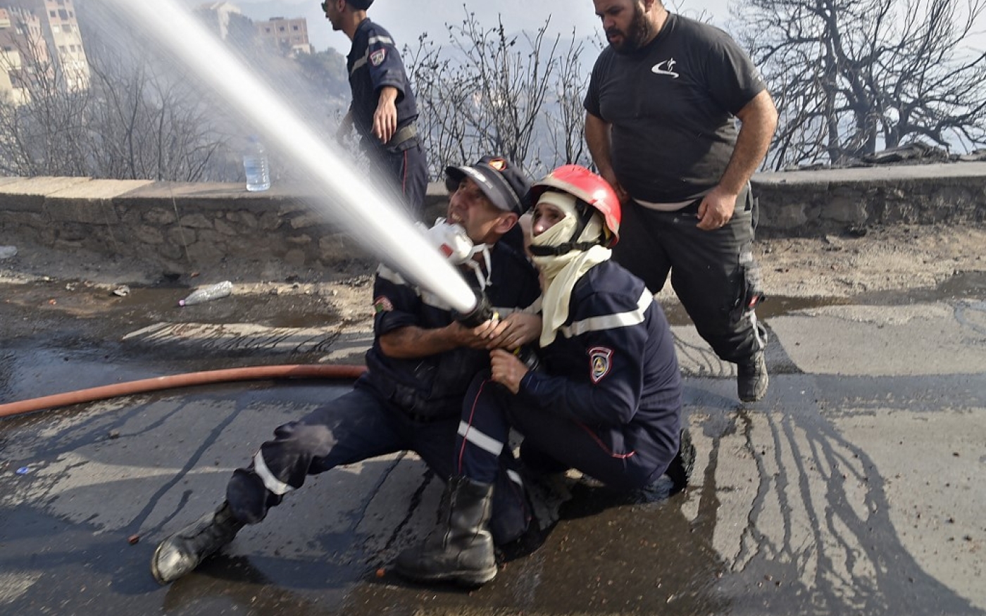 Des pompiers combattent le feu à coups de lance à eau, près de Tizi Ouzou, le 11 août 2021 (AFP/Ryad Kramdi)