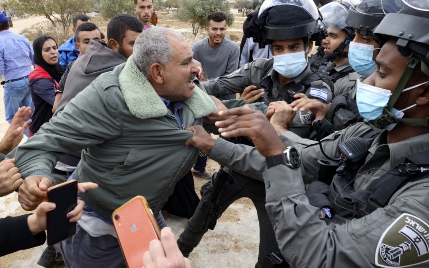 Les forces de sécurité israéliennes arrêtent un Palestinien du village de Susya en Cisjordanie occupée lors d’échauffourées avec des colons juifs de la colonie du même nom, le 24 septembre 2021 (AFP)