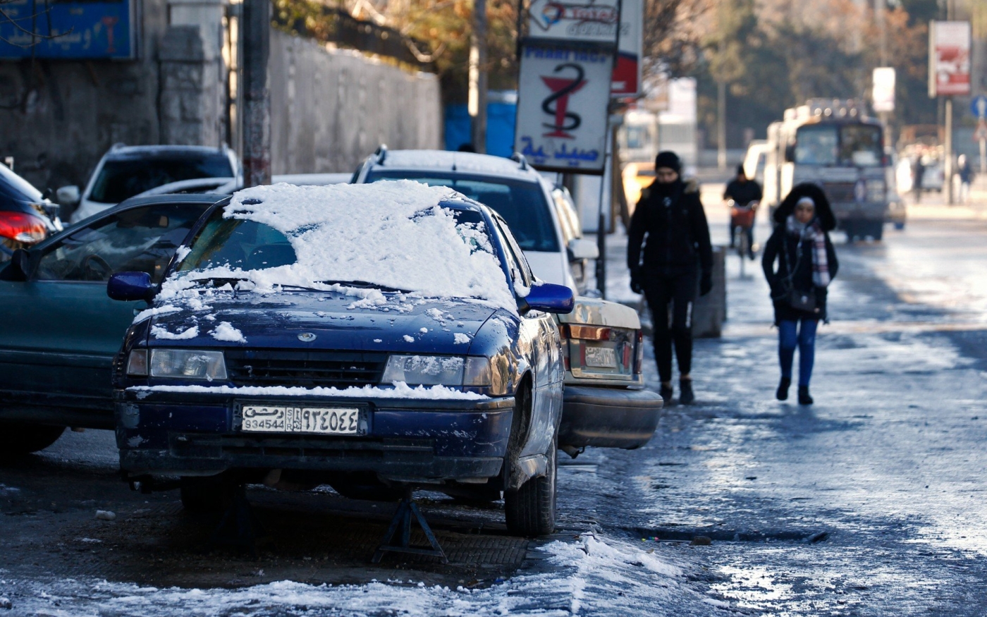 Des Syriens marchent dans la neige à Damas le 20 janvier 2022 (AFP)