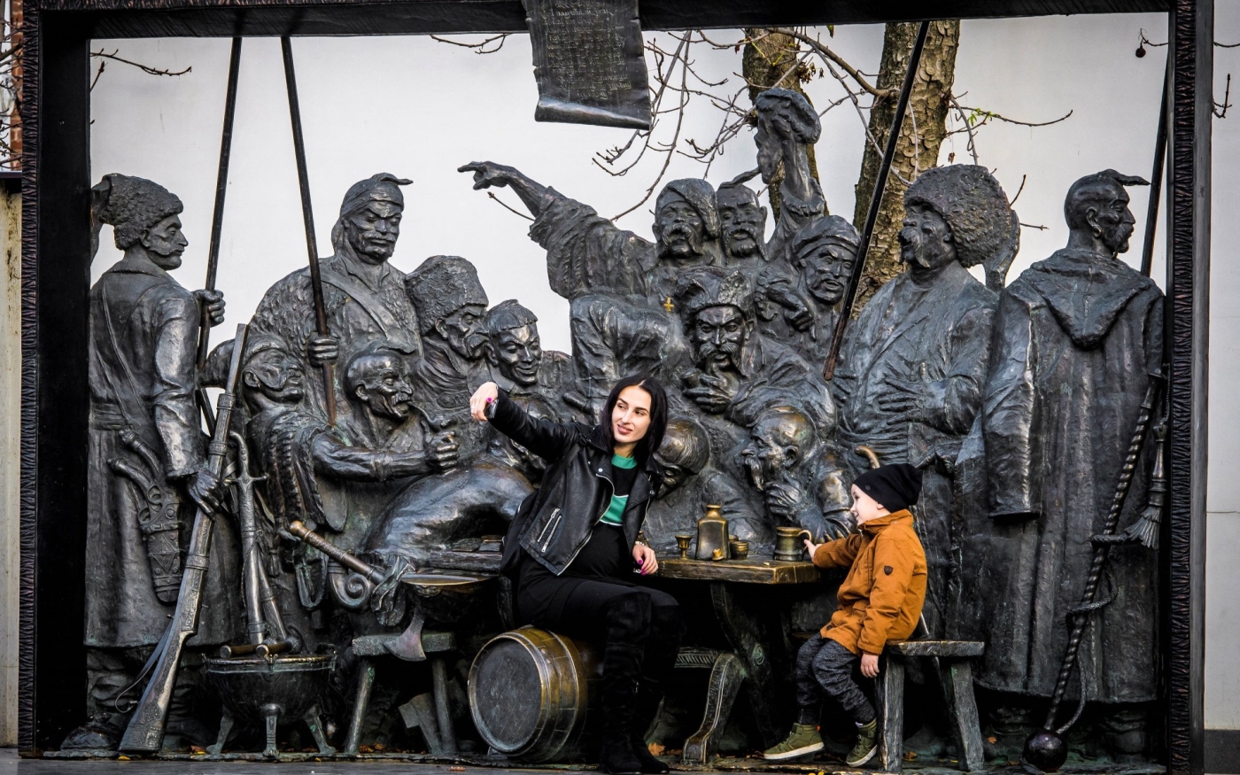 Une femme prend un selfie devant une sculpture qui montre la « Réponse des Cosaques zaporogues au sultan Mehmed IV de l’Empire ottoman » à Krasnodar, en Russie (AFP)