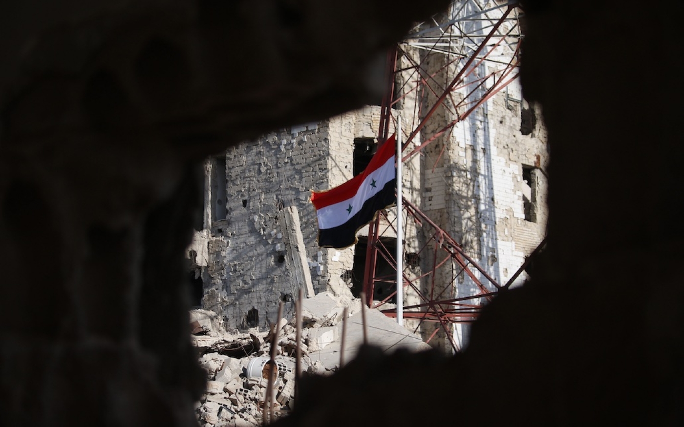 Le drapeau national syrien au milieu des bâtiments endommagés à Deraa-al-Balad, une partie de la ville de Deraa, au sud, détenue par l’opposition, le 12 juillet 2018 (AFP)