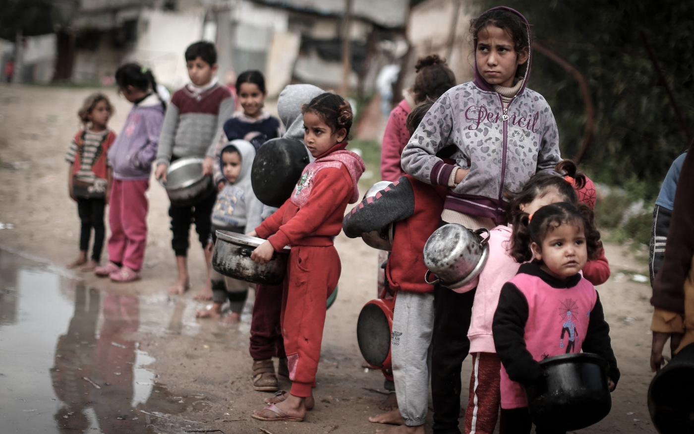 Des enfants palestiniens portant des faitouts attendent de recevoir un repas dans un quartier pauvre de Gaza, le 28 janvier 2021 (AFP)