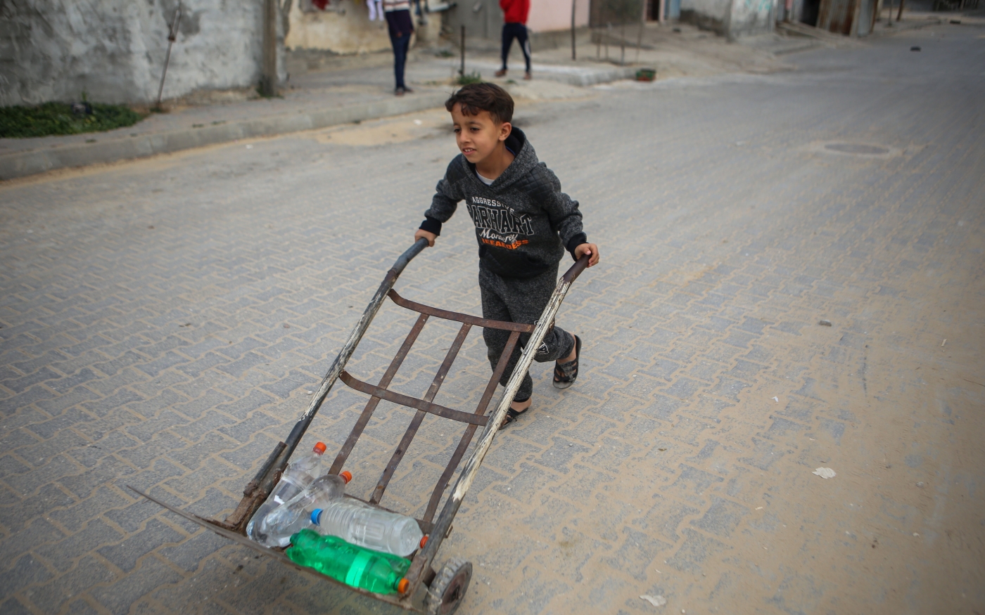 Un jeune Palestinien pousse un chariot contenant des bouteilles d’eau jusqu’au domicile familial dans le camp de réfugiés d’al-Nuseirat, le 15 mars 2019 (MEE/Mohammed al-Hajjar).
