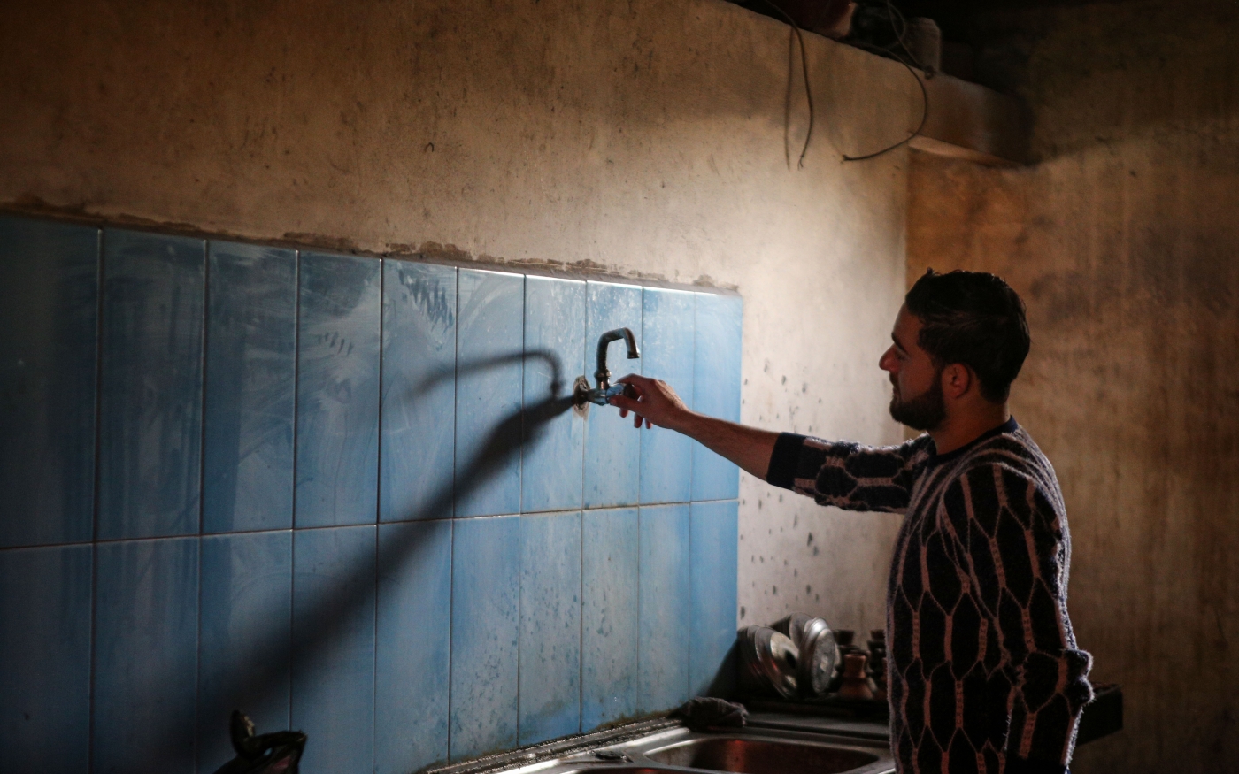 Un Palestinien vérifie le robinet d’eau de sa maison dans le camp de réfugiés d’al-Nuseirat à Gaza, où l’eau est constamment coupée, le 5 mars 2019 (MEE/Mohammed al-Hajjar)