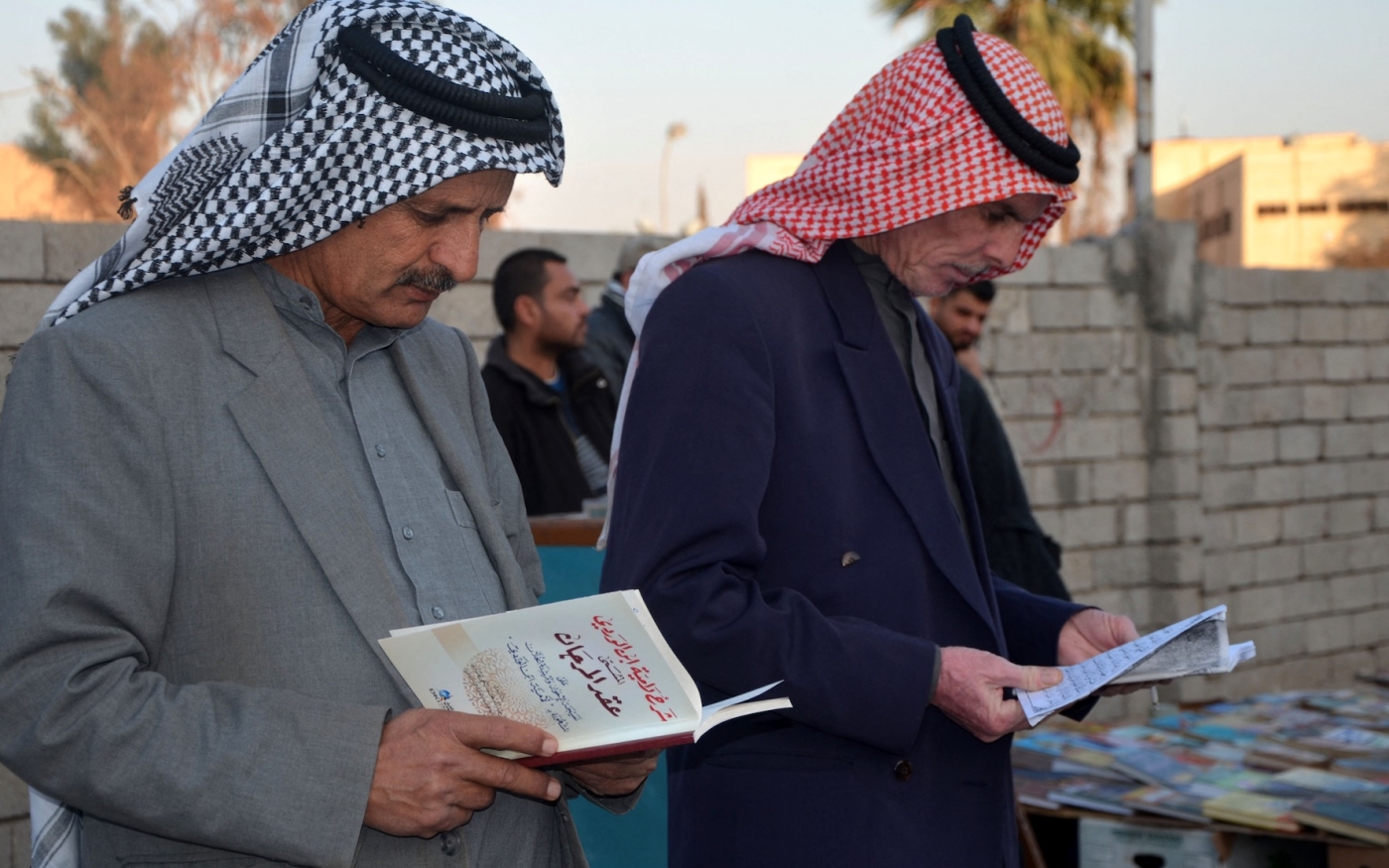 Des Irakiens lisent dans une rue de l’ancienne ville assiégée Mossoul, le 12 janvier 2018 (AFP)