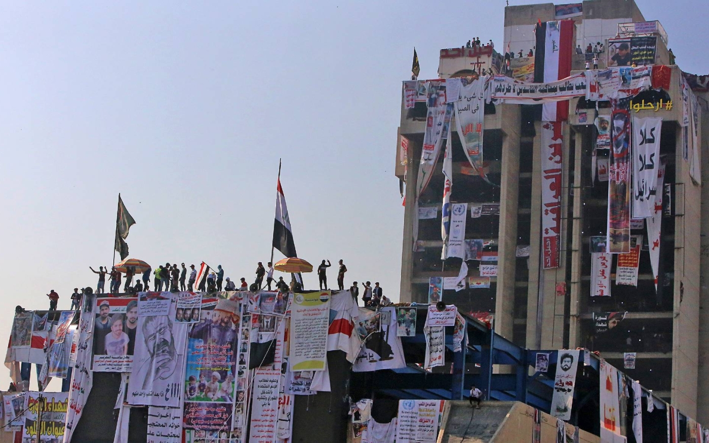 Des manifestants se rassemblent au sommet du bâtiment abandonné du « restaurant turc » sur la place Tahrir de Bagdad, au cours de manifestations anti-gouvernementales en novembre 2019 (AFP)