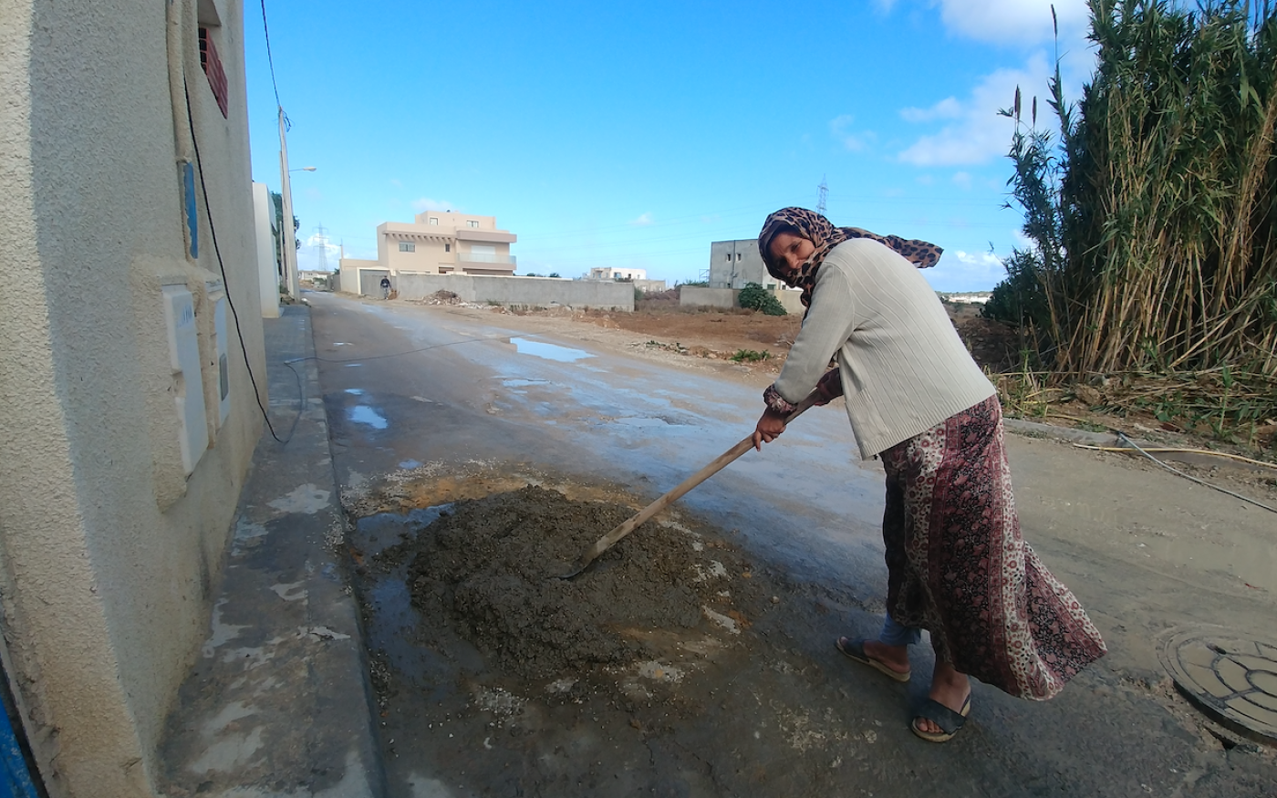 Amina, résidente de Bhar Lazreg depuis 1978, devant sa maison qu’elle répare, avec au fond la terre qu’elle continue de cultiver (MEE/Mathieu Galtier)