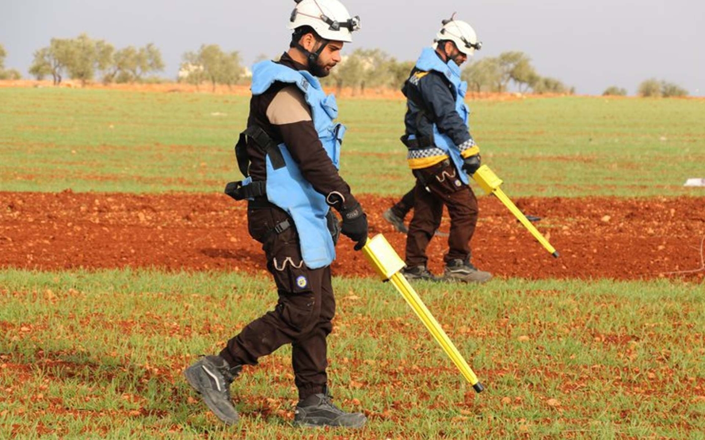 Des volontaires des Casques blancs recherchent des munitions non explosées dans des terres agricoles syriennes (Défense civile syrienne)