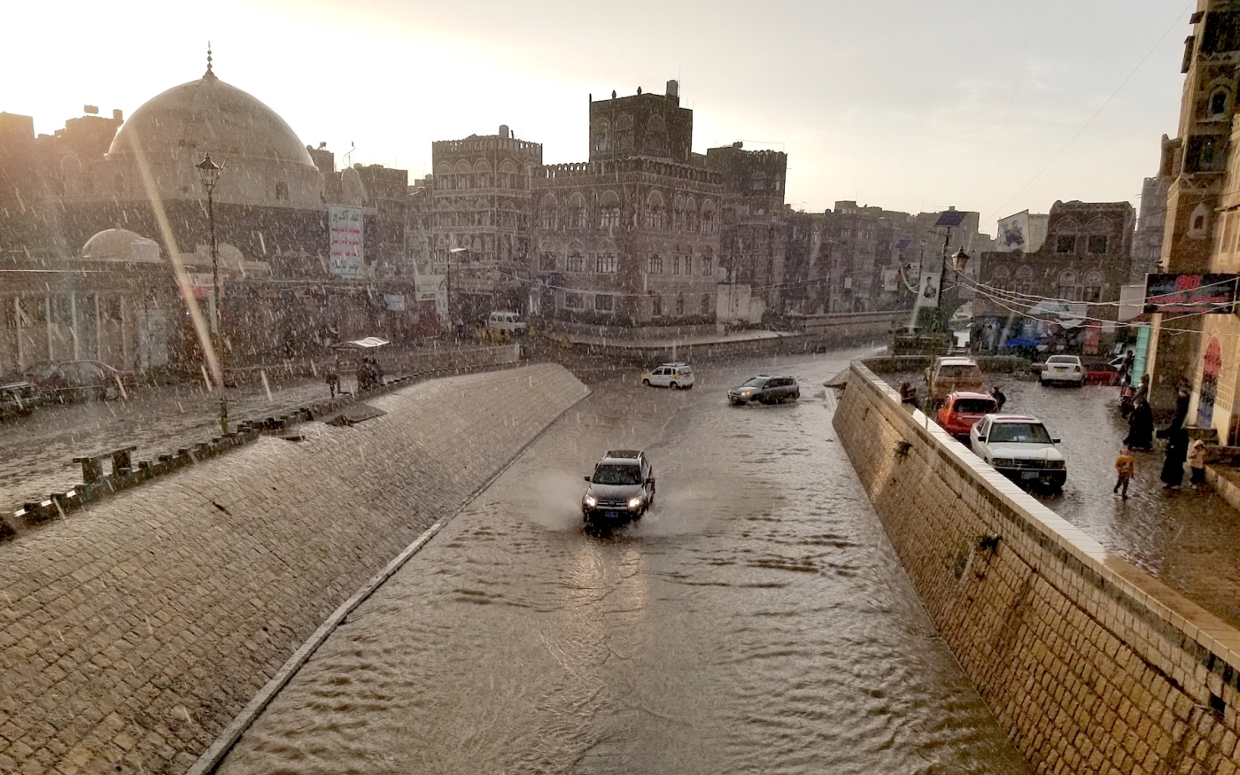 Des voitures passent sur une route inondée dans la vieille ville de Sanaa, qui a connu plusieurs mois de fortes pluies (MEE)