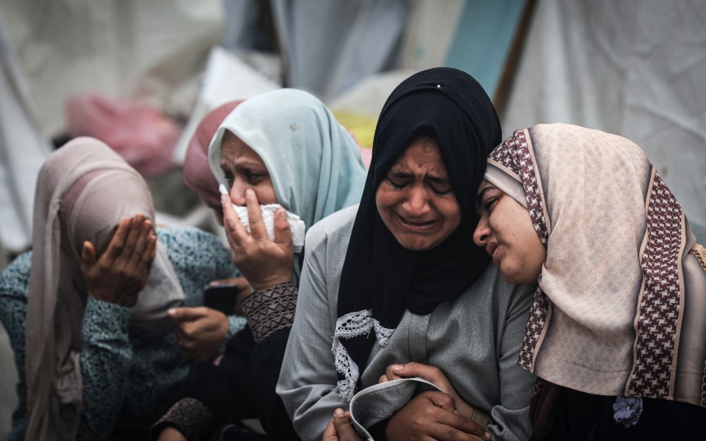 Des Palestiniens pleurent leurs proches, tués lors d’une frappe israélienne nocturne contre le camp de réfugiés d’al-Maghazi, lors de funérailles collectives à l’hôpital al-Aqsa de Deir al-Balah, dans le centre de la bande de Gaza, le 25 décembre 2023 (AFP/Mahmud Hams)
