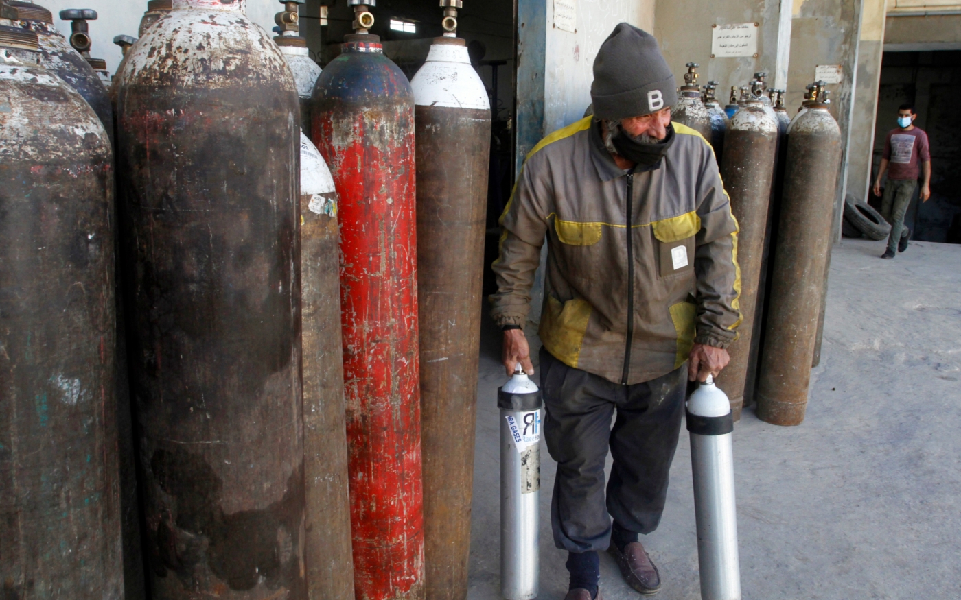 Un employé porte des bouteilles d’oxygène destinées aux hôpitaux traitant les patients atteints de COVID-19, dans une usine de Sidon, au sud du Liban le 9 janvier 2021 (AFP)