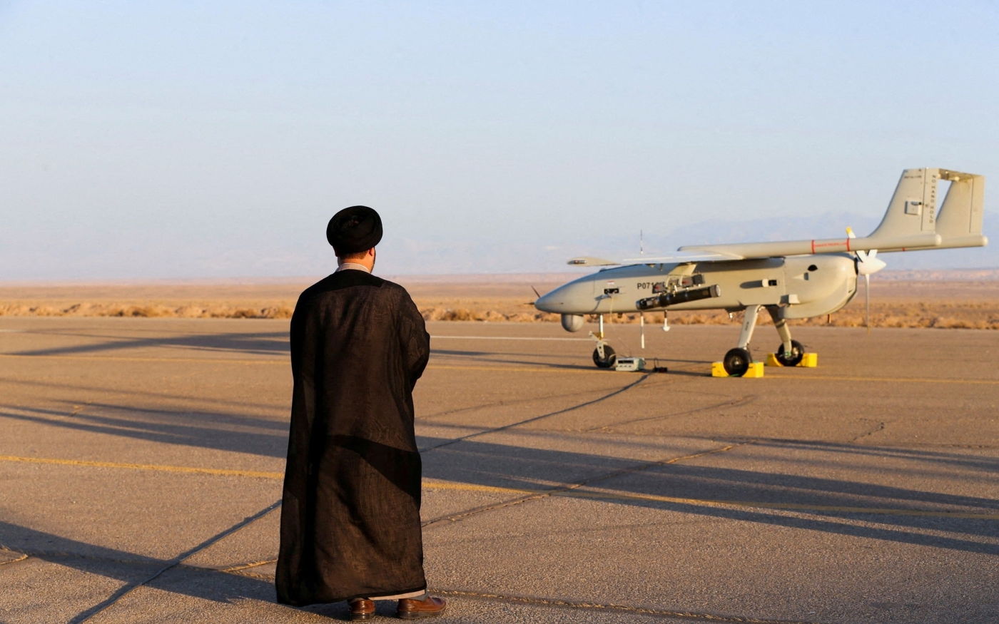 Un ecclésiastique iranien se tient près d’un drone lors d’un exercice militaire dans un lieu non divulgué en Iran, le 24 août (Reuters)
