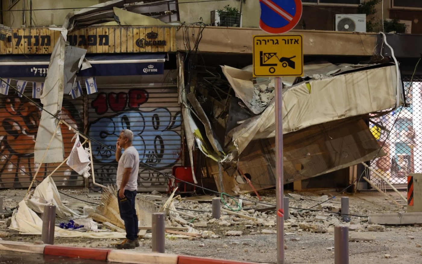 À Tel Aviv, un homme se tient devant un magasin touché par une roquette tirée par des militants palestiniens de la bande de Gaza, le 7 octobre 2023 (Jack Guez)