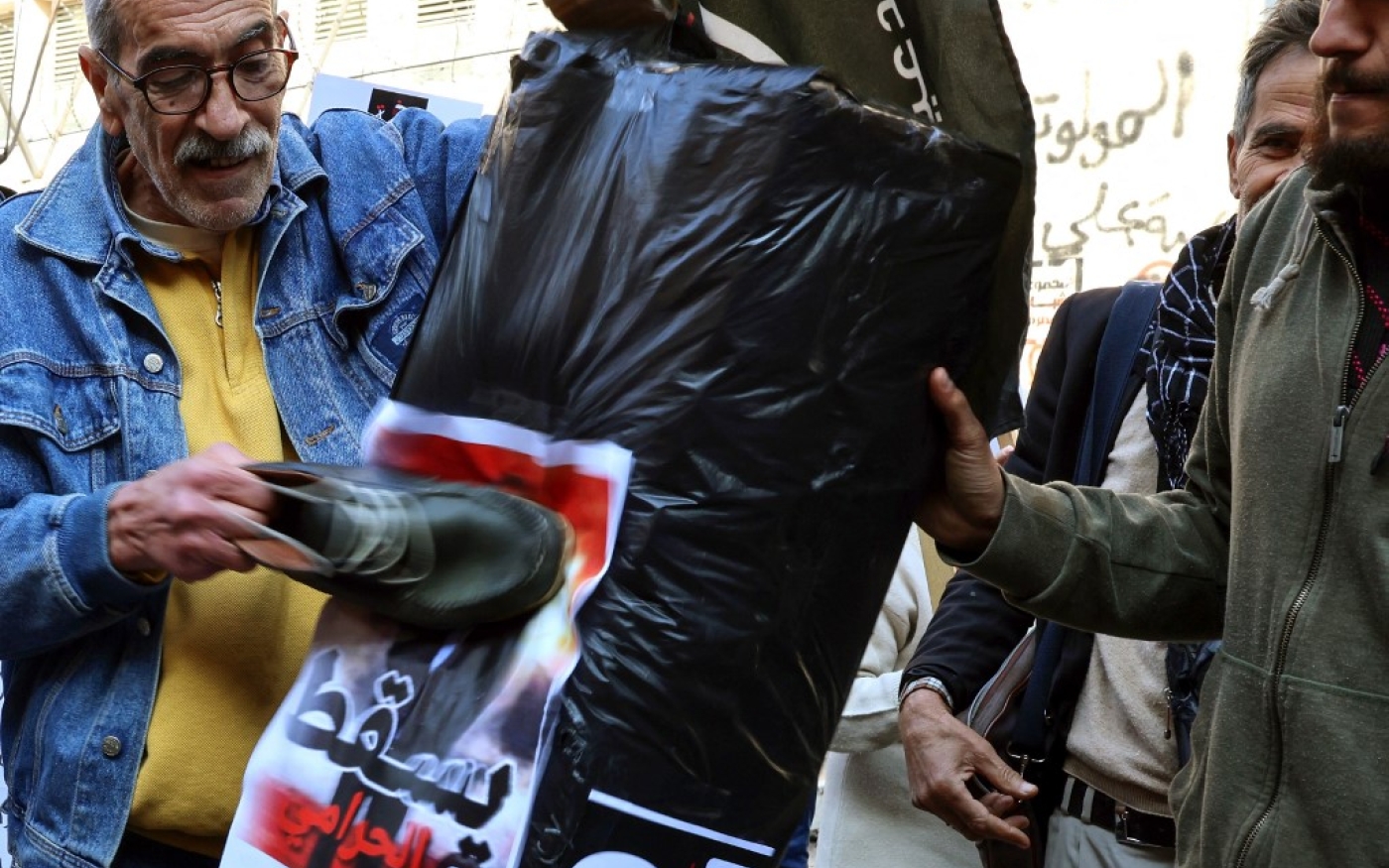 Un manifestant frappe d’une chaussure le portrait du gouverneur de la Banque centrale du Liban pour protester contre sa politique monétaire, à Beyrouth, le 25 janvier 2023 (AFP/Joseph Eid)