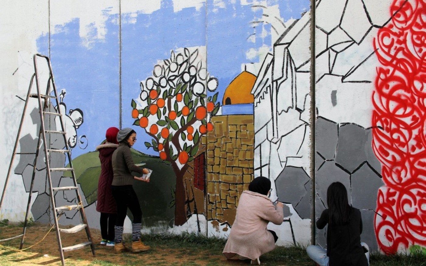 Des artistes libanaises dessinent un oranger de Jaffa et le dôme du rocher sur un mur à la frontière méridionale du Liban avec Israël près de la porte de Fatima, le 17 décembre 2017 (AFP)