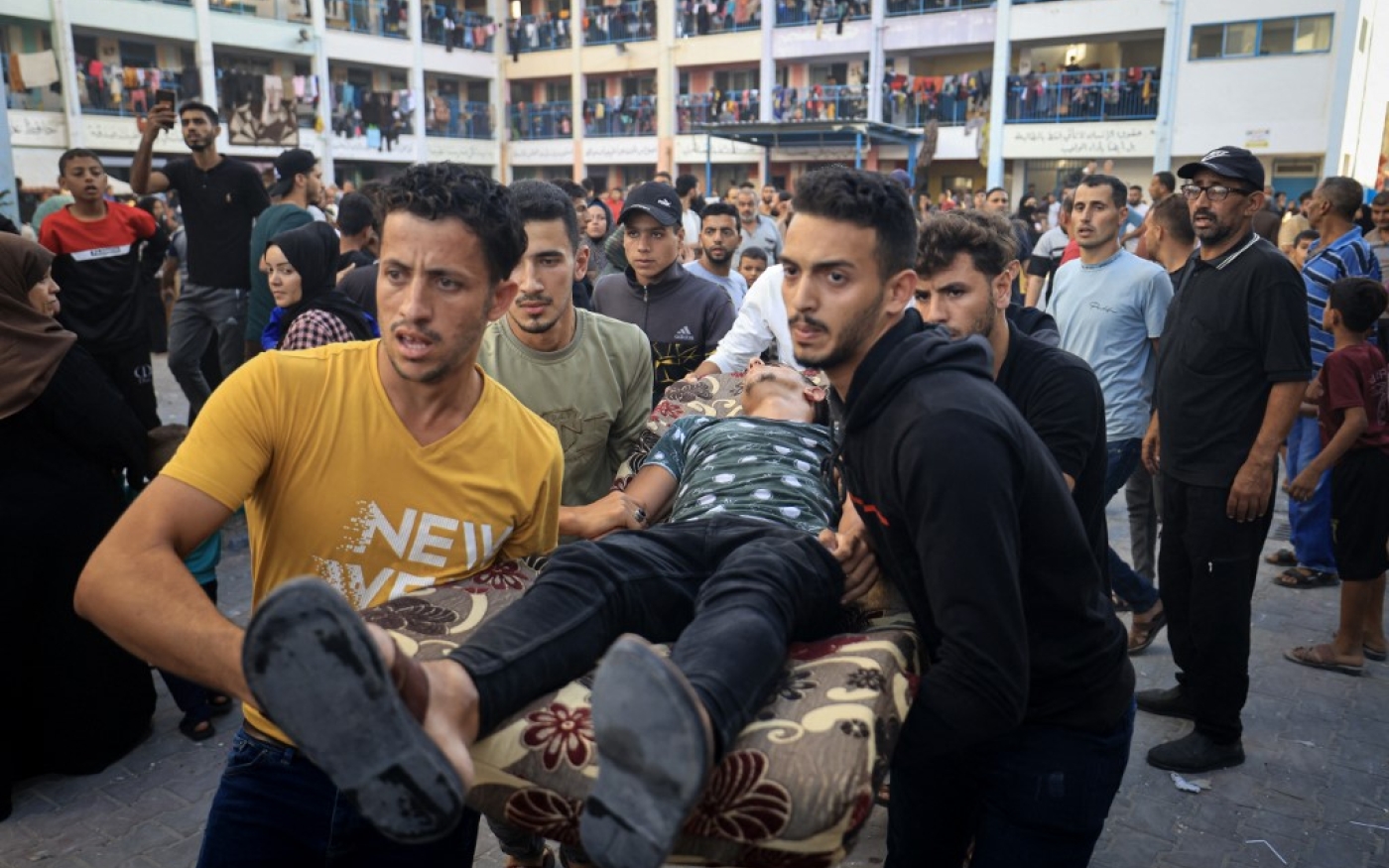 Des Palestiniens évacuent un homme blessé après une frappe israélienne près d’une école de l’Office de secours et de travaux des Nations unies (UNRWA) à Khan Younès, dans le sud de la bande de Gaza, le 21 octobre 2023 (AFP/Mahmoud Hams)