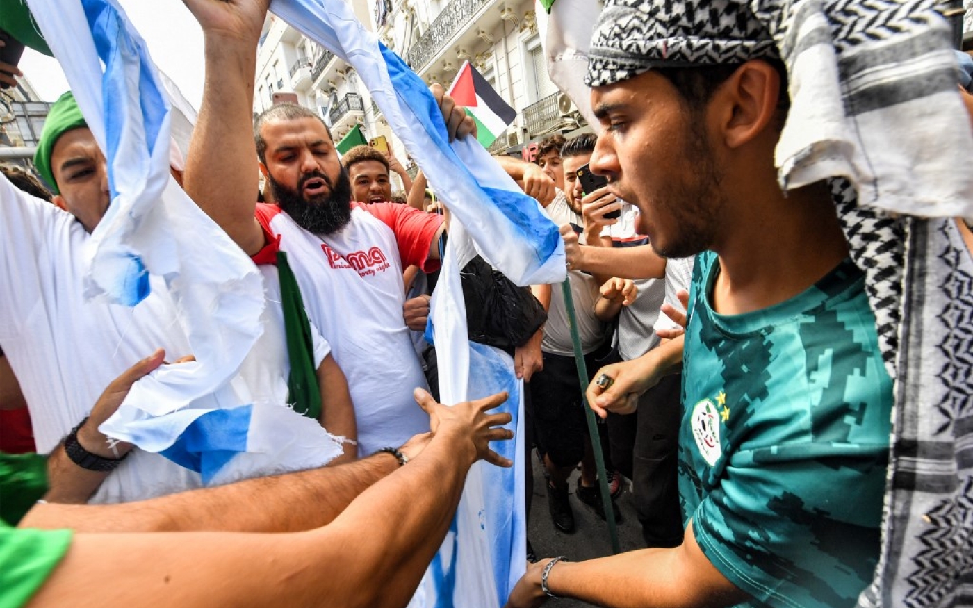 Des manifestants se préparent à brûler un drapeau israélien lors de la manifestation de solidarité avec les Palestiniens à Gaza, à Alger, le 19 octobre 2023 (AFP)