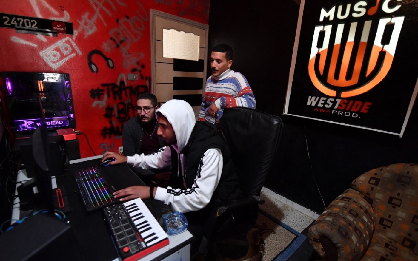 Mohamed Ali Ayari (debout), un rappeur d’un quartier défavorisé de Tunis, se tient dans un studio d’enregistrement à Douar Hicher le 1er mars 2023 (AFP/Fethi Belaid)