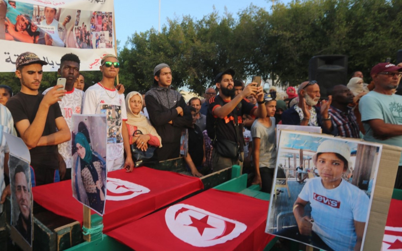 Des Tunisiens entourent de faux cercueils et tiennent des photos des victimes alors qu’ils participent à une manifestation, le 4 novembre 2022, pour exiger des réponses sur le sort de douze personnes qui ont disparu en mer en septembre, dans la ville côtière de Zarzis, dans le Sud-Est de la Tunisie (AFP/Fathi Nasri)