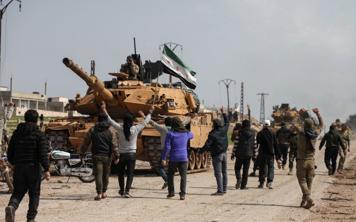 Des Syriens entourent un char turc dans le nord de la Syrie, le 15 mars 2020 (AFP)