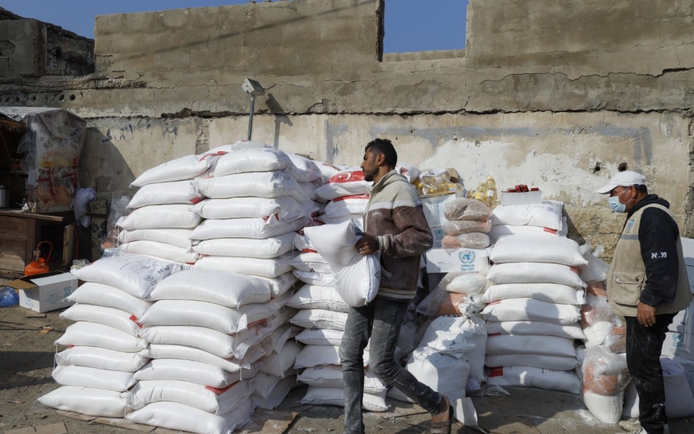 Des employés de l’UNRWA empilent des rations alimentaires devant un centre d’aide de l’organisation à Gaza, le 12 décembre (AFP) 