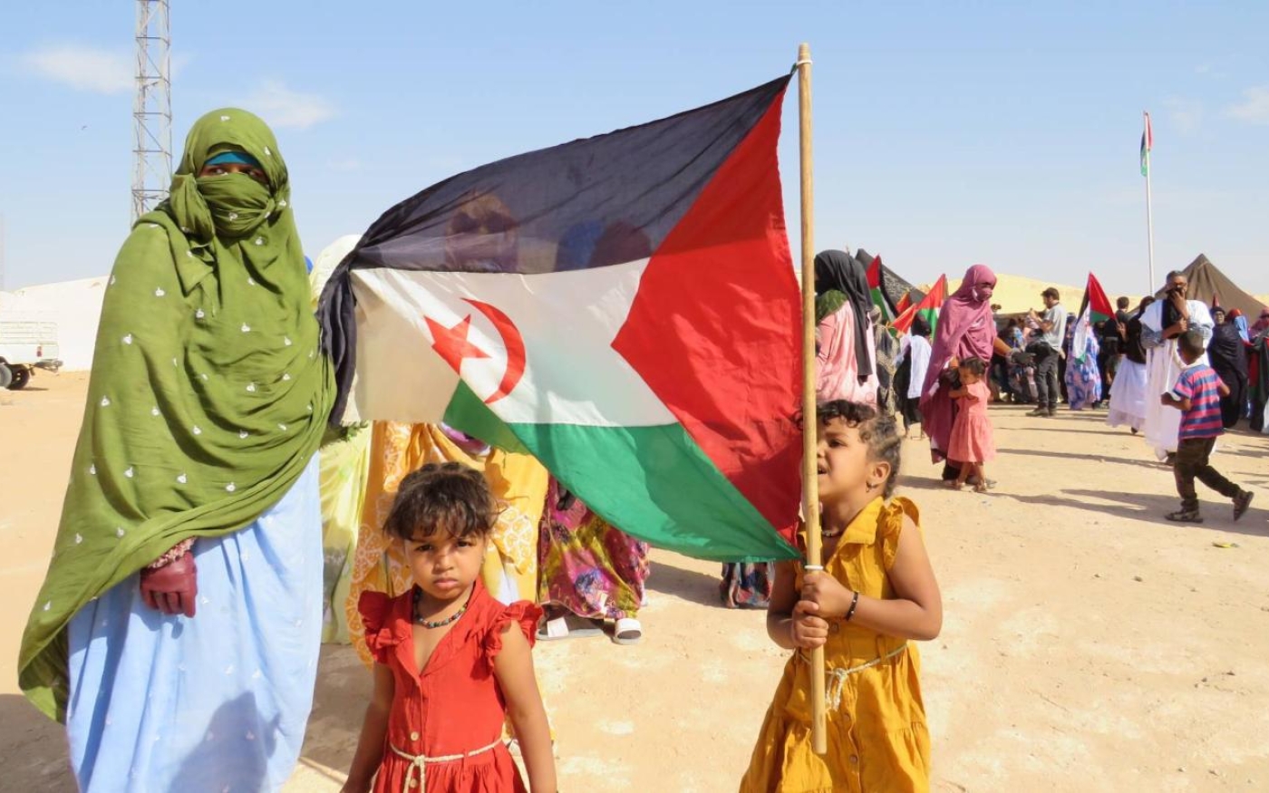 Une réfugiée sahraouie et ses enfants brandissent le drapeau du Front Polisario dans le camp de Bojador, en Algérie (MEE/Daniel Hilton)