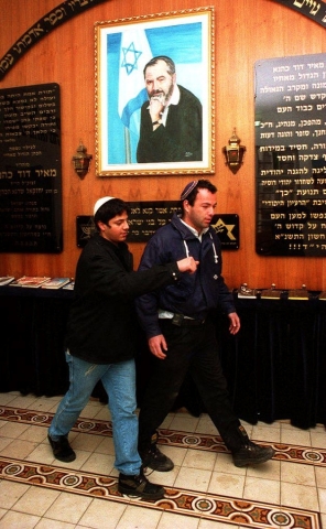 A young Itamar Ben Gvir, left, and fellow Kach activist Avishsai Raviv pass under a poster of their leader Meir Kahana in the movement office in Jerusalem on 13 March 1995 (AFP)