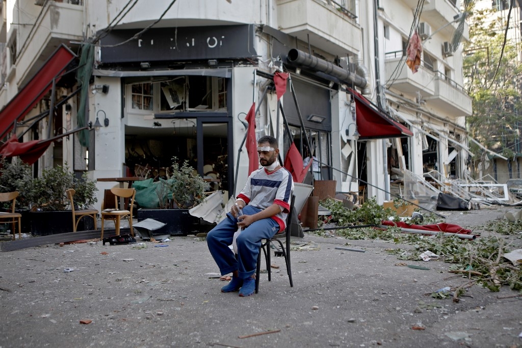 Mercredi 5 août 2020. Le lendemain des explosions, un homme blessé est assis à côté d’un restaurant dans le quartier branché de Mar Mikhael à Beyrouth, partiellement détruit (AFP)